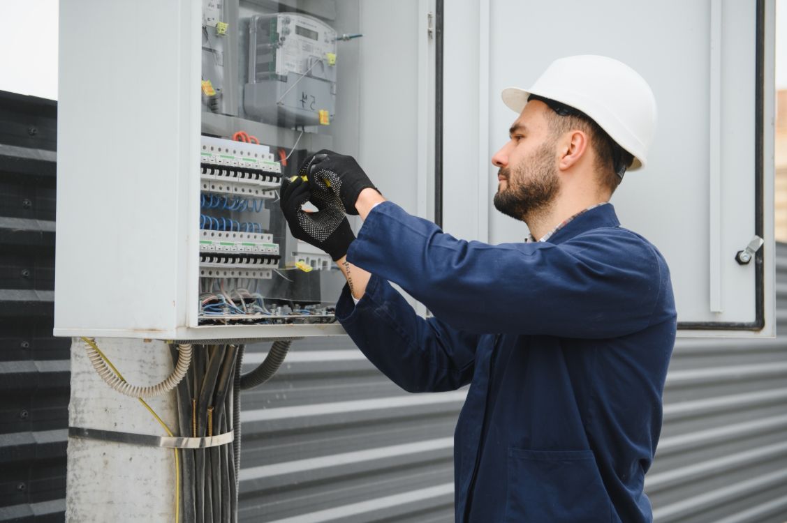 An electrical  trainee at work in a hard hat 